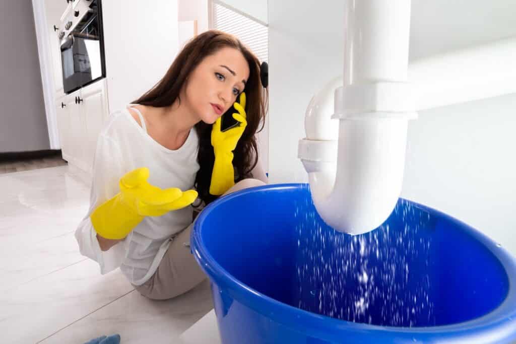 Woman Calling Plumber To Fix Sink Pipe